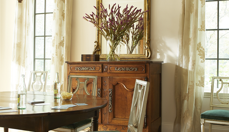 Comedor elegante con paredes de color blanco hueso, muebles de madera mixtos, detalles dorados 