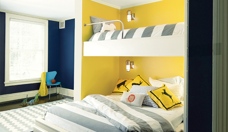 Un dormitorio para niños pintado de amarillo con literas grises y blancas.