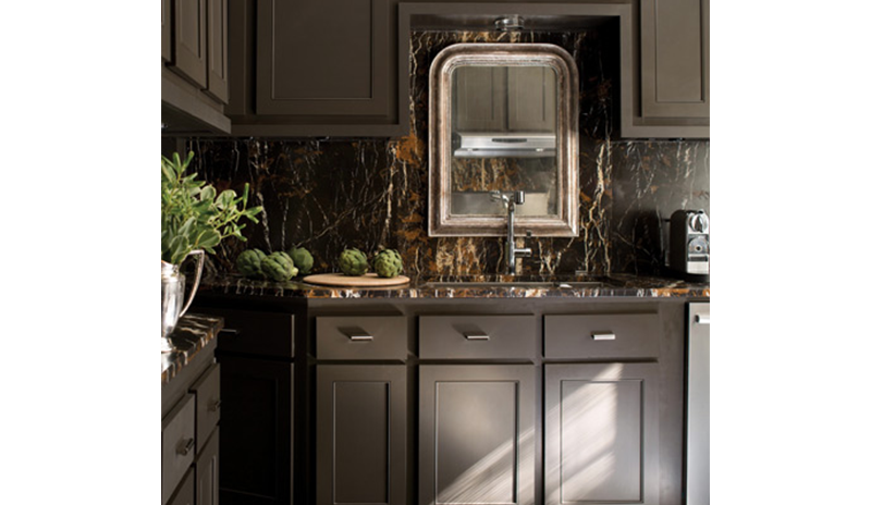 Rich brown kitchen cabinets, brown marble backsplash and an ornate mirror create a sumptuous culinar