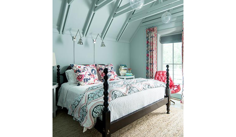 Vibrant blue bedroom with matching industrial ceiling including a large bed with printed bedding.