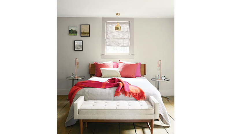 A relaxing bedroom with light gray walls, full size bed with pink pillows and a throw blanket.