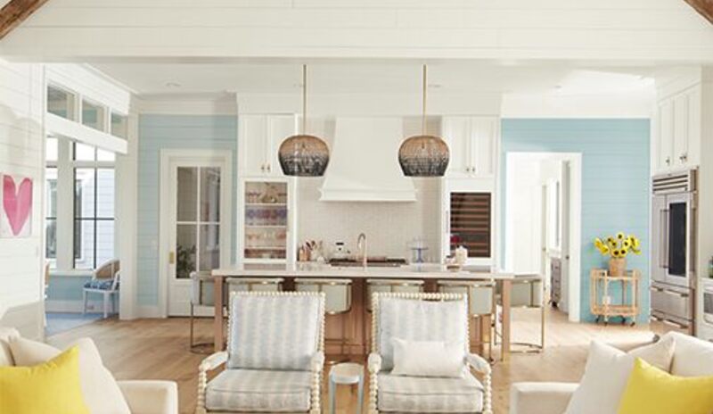 An airy, open white-painted living room and kitchen with shiplap walls and vaulted ceiling