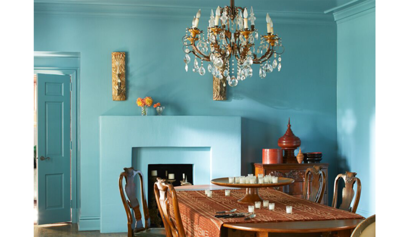 Comedor opulento azul con lámpara de araña, mesa y sillas de madera. Clásico con toque exótico
