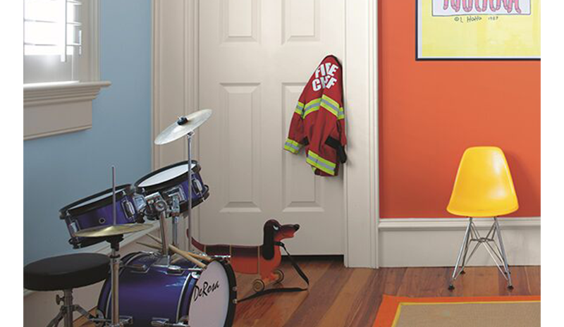 Play area: orange & blue walls, dinosaur painting, yellow chair, blue drum set, child's fireman jack