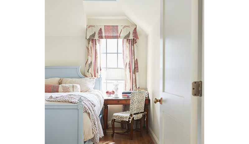 Dormitorio crema, techo celeste, cama azul y cortinas y cojines rosados.