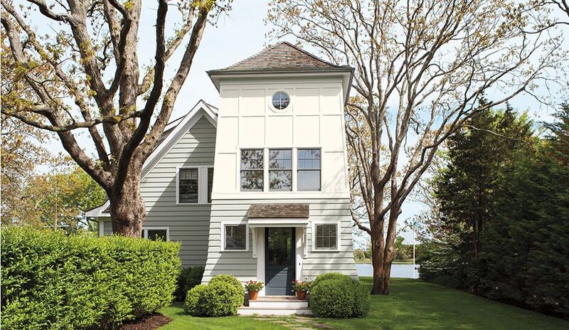 Una casa junto al lago pintada en dos tonos, con color blanco crema y una puerta de color gris 