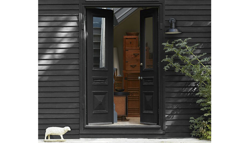 Una casa con exterior pintado de negro, con puertas frontales abiertas también pintadas de negro