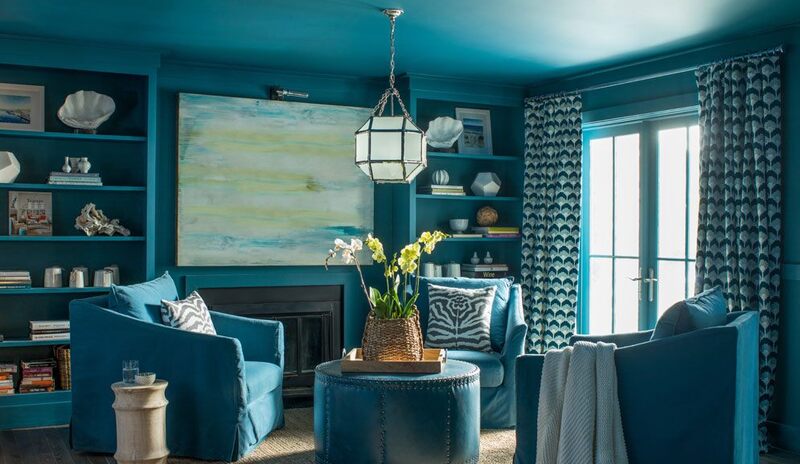 Una sala de estar pintada completamente de azul con sillones de club azules y estanterías empotradas