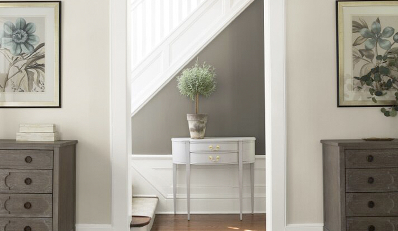 Un pasillo gris y neutro conduce a una escalera blanca.