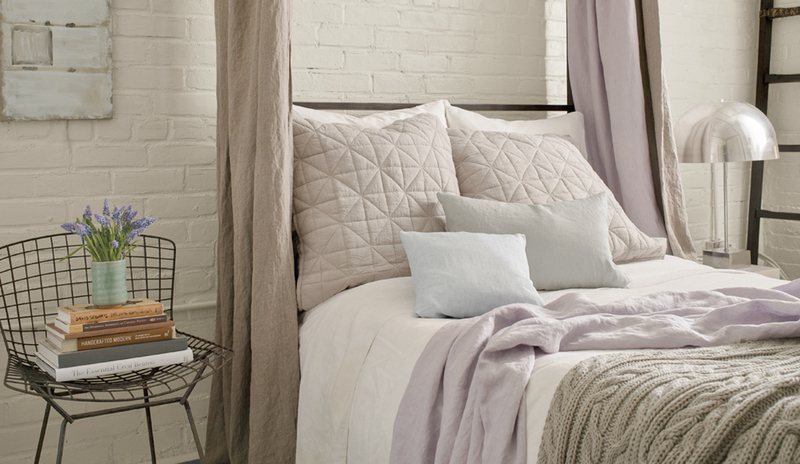 Dormitorio con una pared de ladrillos blancos detrás de una cama con dosel color canela.
