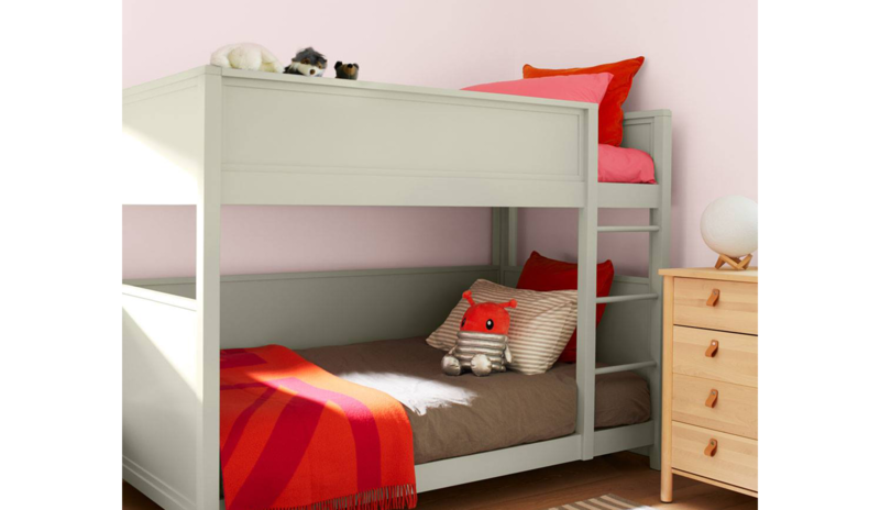 Children’s bedroom with a soft green-painted bunk bed, light pink walls, a blonde wood dresser
