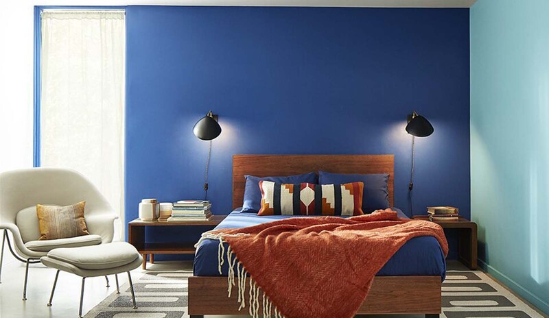 A contemporary bedroom with a dark blue painted wall, a light blue painted wall, a white ceiling