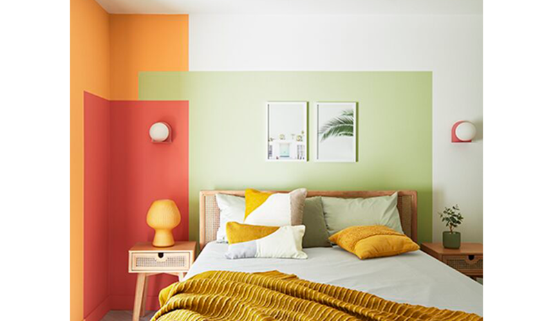 Un dormitorio pequeño con un diseño de pared de bloques de colores verde, rojo y naranja.