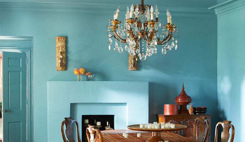 Un opulento comedor con paredes, techo y chimenea pintados de azul.