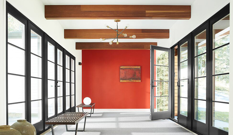 Un pasillo pintado de blanco con una pared decorativa en rojo, techo con vigas de madera
