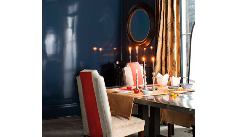Comedor con paredes de color azul brillante con una mesa de comedor con sillas detalles en naranja