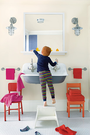 En el baño rosa pálido, un niño pequeño hace su rutina matutina frente al lavabo.