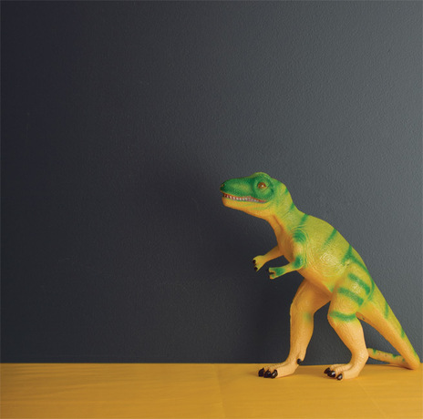 Una pared de tonos profundos enmarca un dinosaurio de juguete.