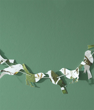 Una pared pintada de verde claro es el telón de fondo de una pancarta de origami.
