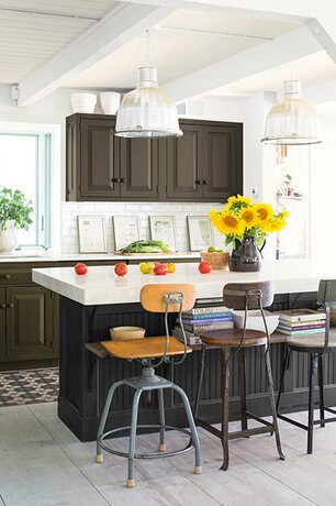 An airy industrial style kitchen taps into deep colors, from a black based kitchen island to deep gr