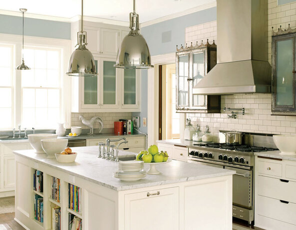 An industrial-style kitchen features painted white cabinets, light blue walls and a subway tile back