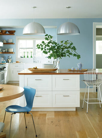 A contemporary kitchen with white cabinets and light blue painted walls is bright and airy.