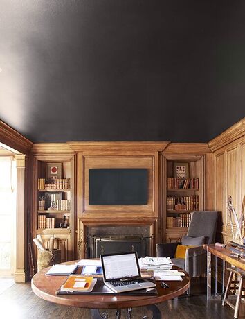 Rustic mahogany study with black ceiling and fireplace.