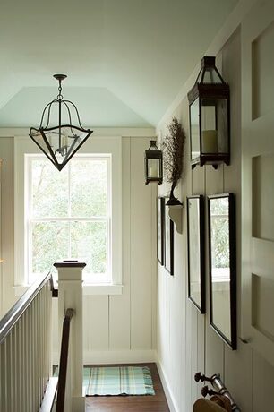 Una escalera de color blanquecino con techo azul claro adornado con una lámpara colgante de vidrio.