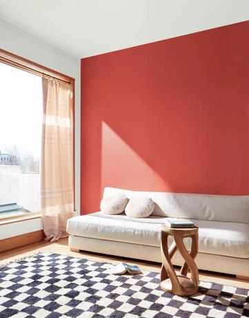 Pared decorativa pintada con Raspberry blush en la sala de estar con sofá blanco 