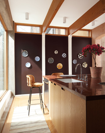 Cocina con pared decorativa pintada de marrón wengué y platos decorativos colgantes.