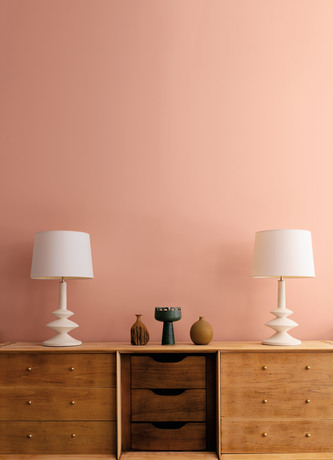 White lamps and décor atop a wooden sideboard in front of a Conch Shell pink-painted wall.