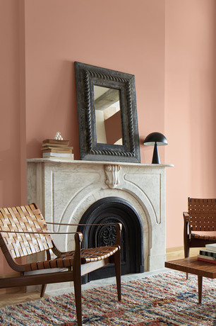 Conch Shell pink-painted living room with marble fireplace, relaxed seating, dark mirror and books.