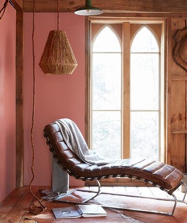 Un diván de cuero vintage contra paredes pintadas de rojo con toques de rosa y naranja