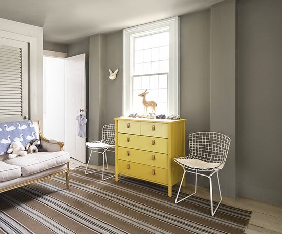 Zona de estar: paredes grises, sofá greige, sillas de metal con cesta, cómoda amarilla y decoración