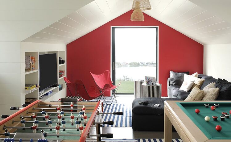 Game room w/ red accent wall, pool & foosball tables, leather sofas, chairs, big TV & striped tables