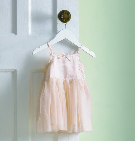 A pale green-painted wall frames a toddler's tutu.