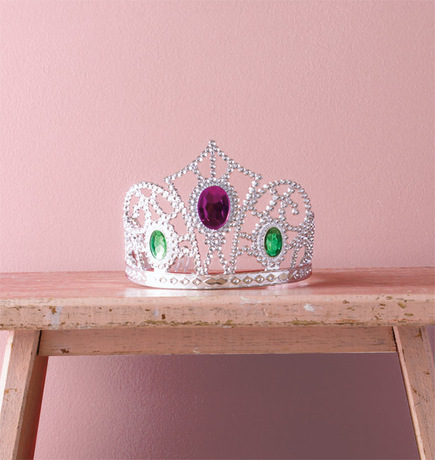 Una pared de tono rosa resalta una tiara engastada en joyas.
