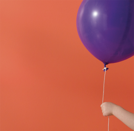 An orange-painted wall frames a purple balloon.