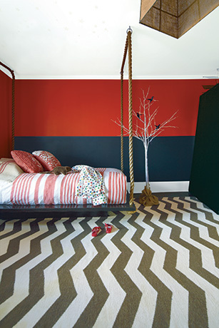 A kid's bedroom with a red and black painted wall features a swing bed.