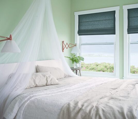 Dormitorio verde con cama junto a la ventana.