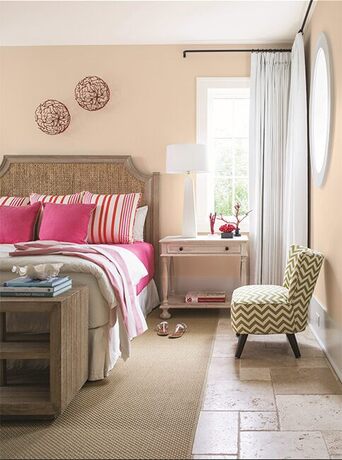 Dormitorio con paredes de durazno claro, acentos rosados y suelo de baldosas de piedra.