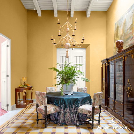 Comedor amarillo con techo y puertas blancas, mesa con mantel turquesa y sillas, gabinetes grandes