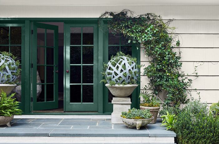 Rich, dark-green painted french doors opened to a gray slate landing with large plant-filled