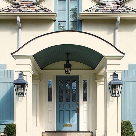 Una hermosa casa pintada de blanco con una puerta frontal, molduras y persianas de color azul claro.