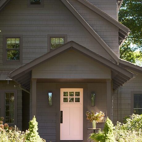 A soothing pink-painted front door makes a lovely contrast on this soft black-painted house