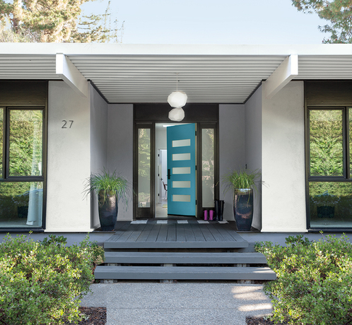 This picture is of a modern gray one story house with a teal door