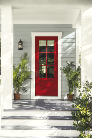 Una puerta principal roja contrastando con un agradable fondo gris.
