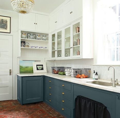Una cocina espaciosa con paredes, molduras y techo pintados de blanco, y gabinetes pintados de azul 