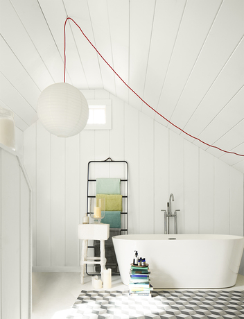 Un luminoso baño pintado de blanco con paredes y techo de tablones de madera, una lámpara
