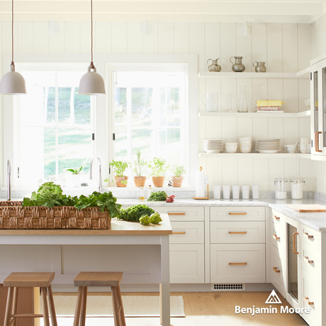 A sun-drenched kitchen with white-painted walls, cabinets, open shelving and a center island